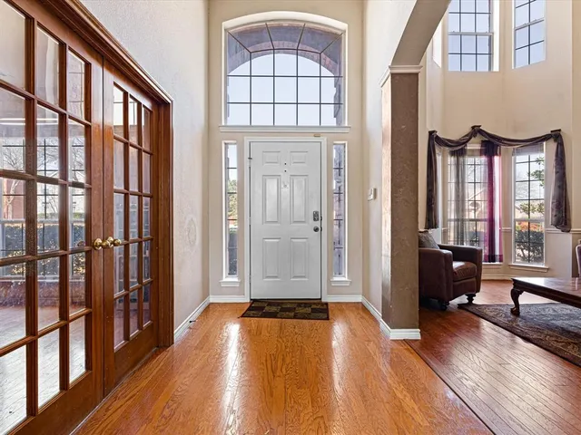 a view of front door with hallway and wooden floor