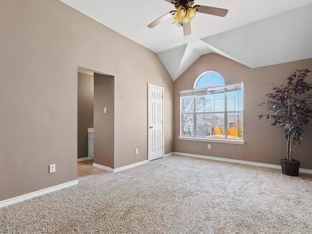 an empty room with windows and chandelier fan