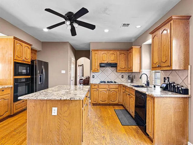 a kitchen with stainless steel appliances granite countertop sink stove refrigerator and cabinets