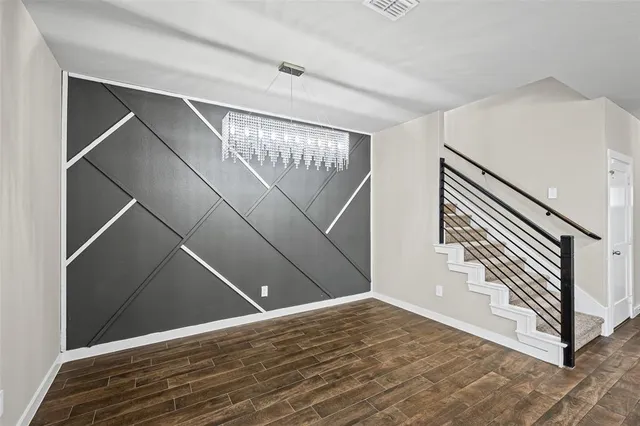 a view of an empty room with stairs and wooden floor
