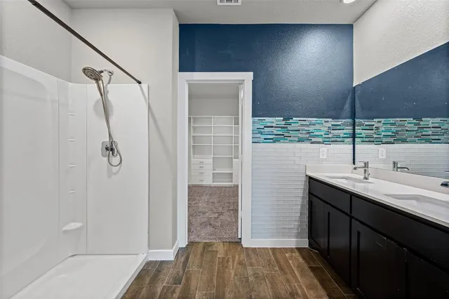 a bathroom with a double vanity sink a shower and a mirror
