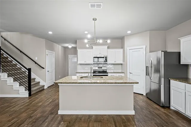 a kitchen with stainless steel appliances granite countertop a refrigerator a stove a sink dishwasher and a refrigerator with wooden floor