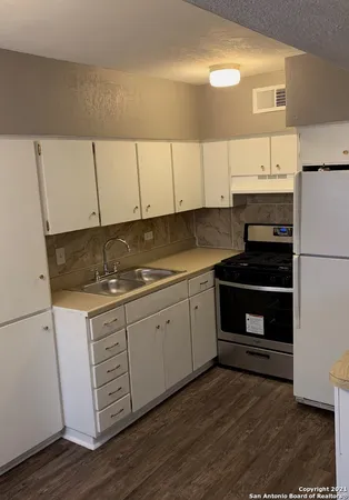 a kitchen with granite countertop white cabinets and white appliances