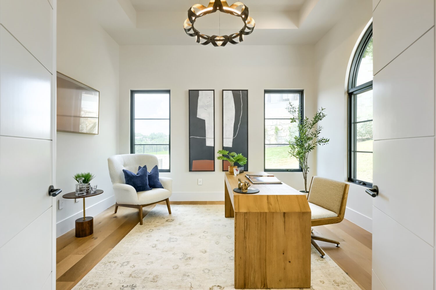 8132 Magnolia Ridge Cove Austin, TX 78738 - Photo 19 of 38 An inviting office space features a warm wooden desk, large windows, and a sophisticated light fixture illuminating the vaulted ceiling.