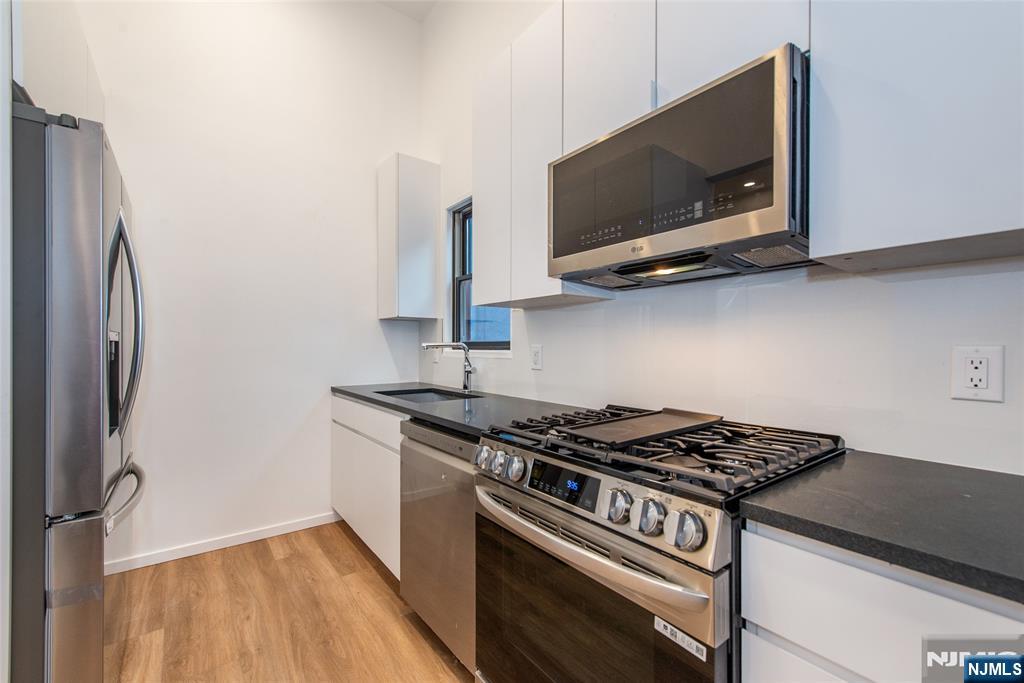206 Harrison Avenue, Unit 1 Harrison, NJ 07029 - Photo 3 of 10 a kitchen with stainless steel appliances a sink and a microwave