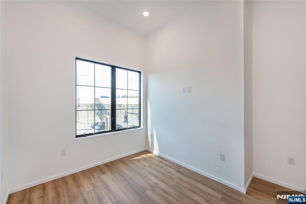 206 Harrison Avenue, Unit 1 Harrison, NJ 07029 - Photo 7 of 10 an empty room with wooden floor and windows