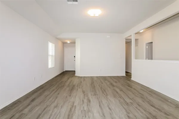 a view of an empty room with wooden floor and a window