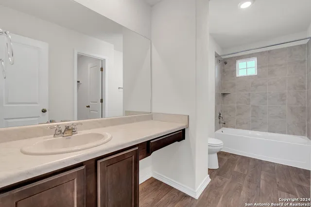 a bathroom with a sink a toilet a mirror and bathtub