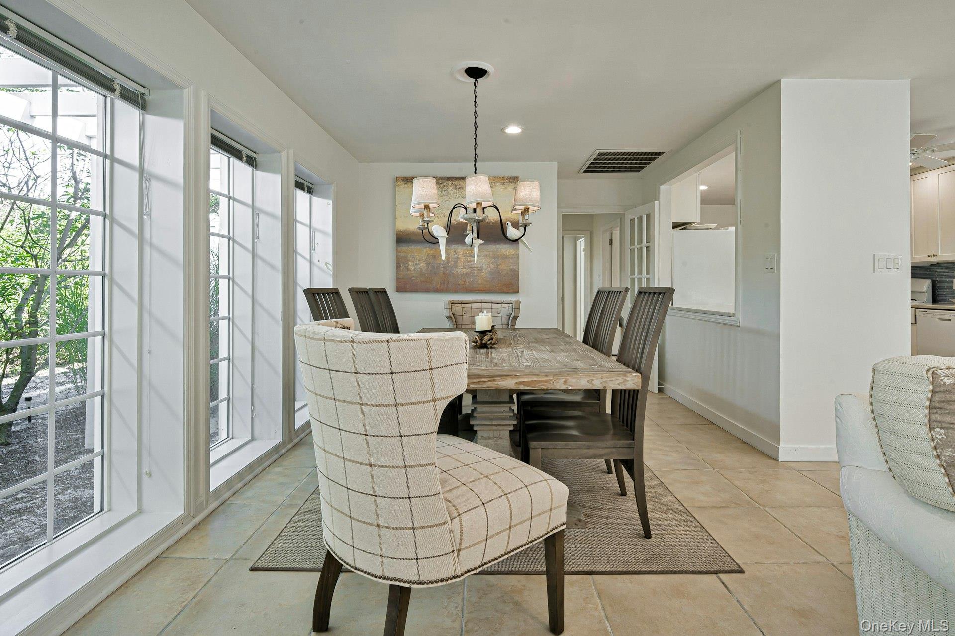 39 Sloop Walk Ocean Beach, NY 11770 - Photo 16 of 46 Dining area featuring large grid-pattern windows, a rustic wood-finish dining table, and tile flooring