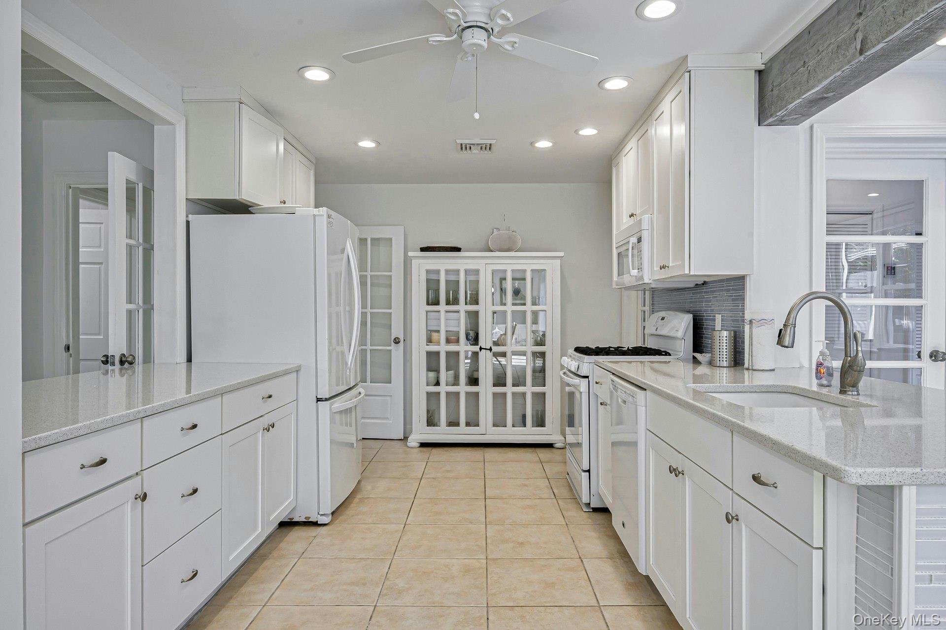39 Sloop Walk Ocean Beach, NY 11770 - Photo 19 of 46 Modern kitchen featuring white cabinetry, light-toned countertops, and tile flooring