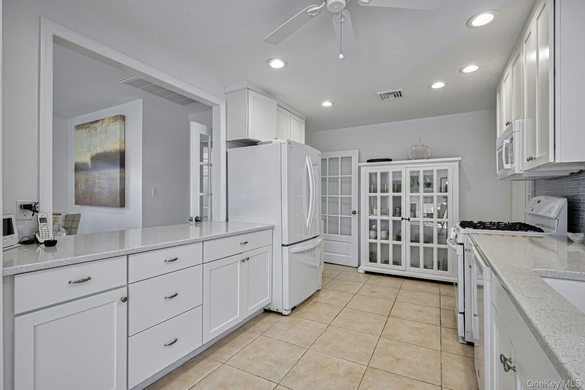 39 Sloop Walk Ocean Beach, NY 11770 - Photo 24 of 46 Kitchen featuring white cabinetry, light-toned countertops, recessed lighting, tile flooring, and an architectural opening