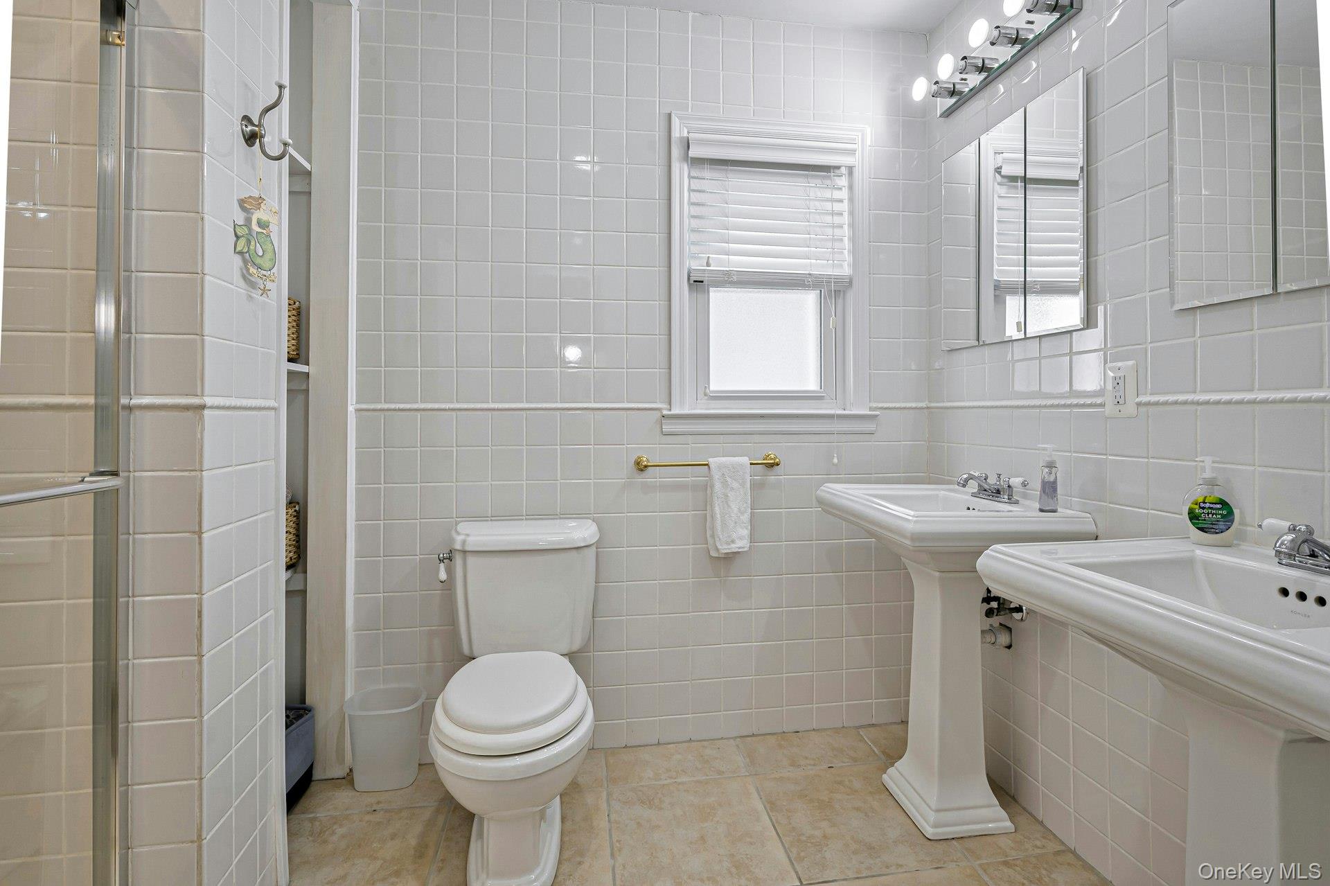 39 Sloop Walk Ocean Beach, NY 11770 - Photo 27 of 46 Bathroom featuring two pedestal sinks, a toilet, and a glass-enclosed shower