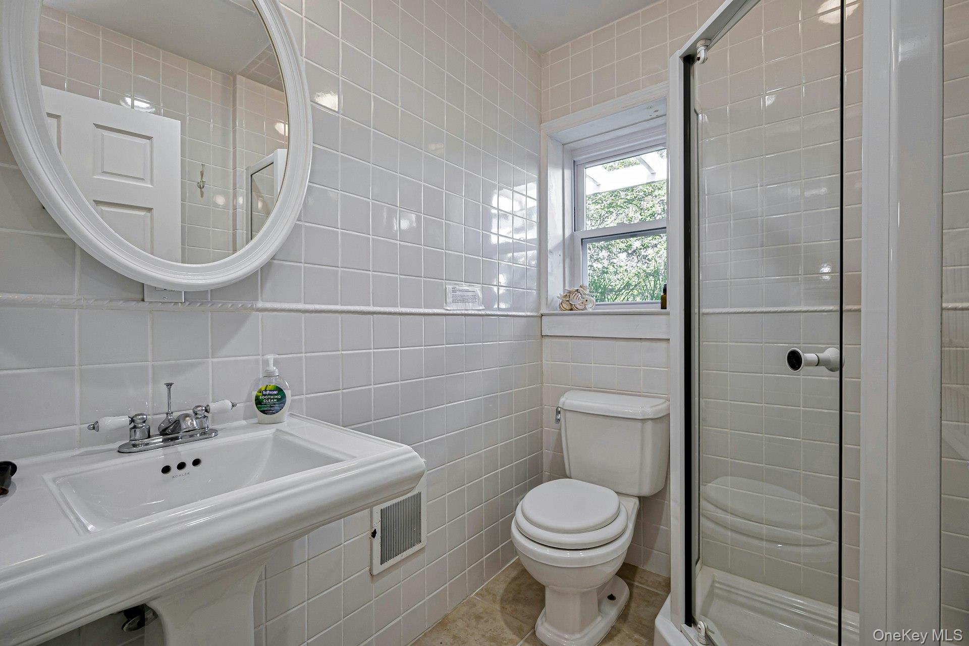 39 Sloop Walk Ocean Beach, NY 11770 - Photo 30 of 46 Bathroom featuring a pedestal sink, oval framed mirror, tiled walls, and a glass-enclosed shower