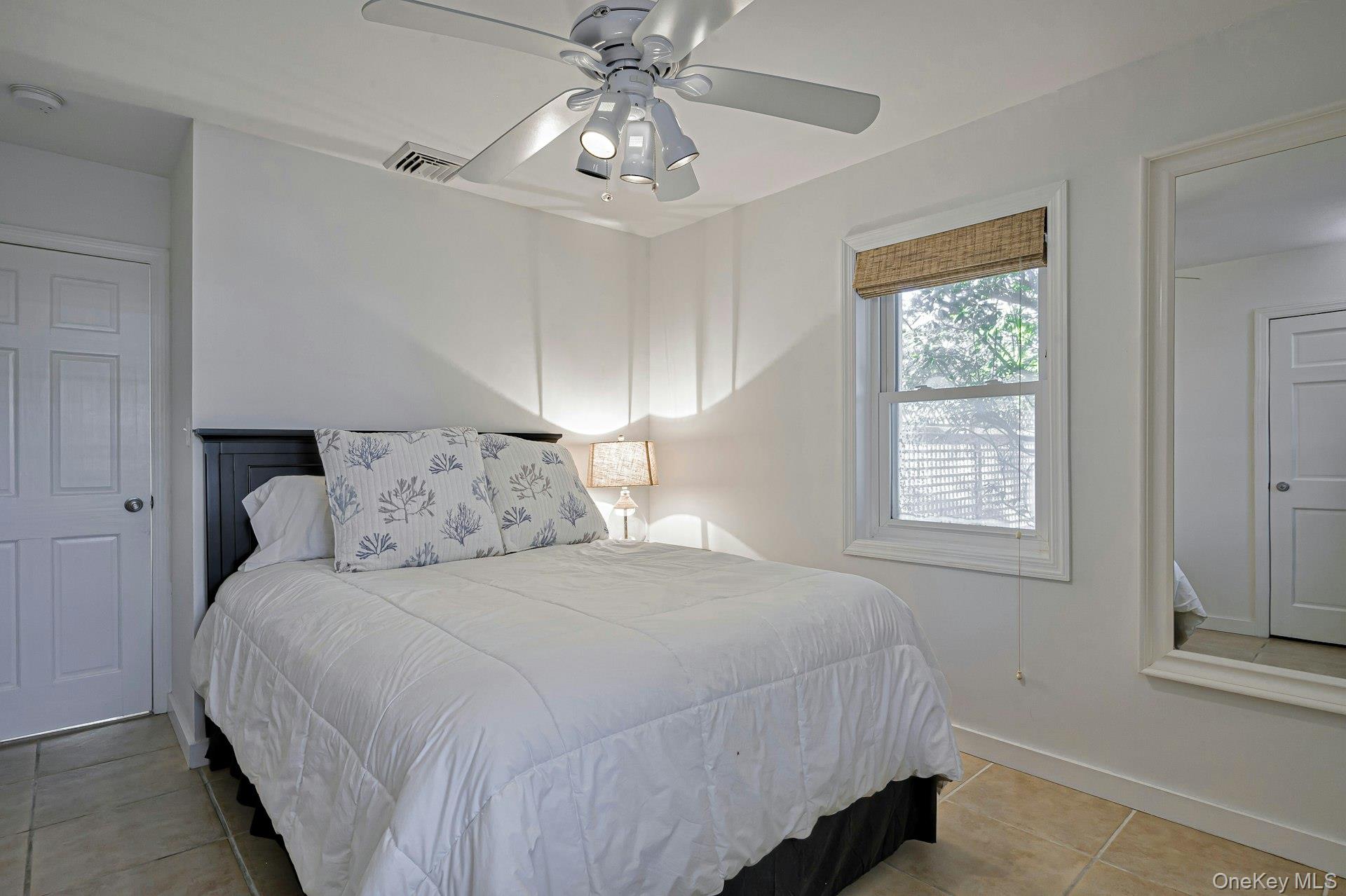 39 Sloop Walk Ocean Beach, NY 11770 - Photo 33 of 46 Bedroom featuring ceramic tile flooring, a window with a woven shade, a ceiling fan with integrated lighting, and white paneled doors