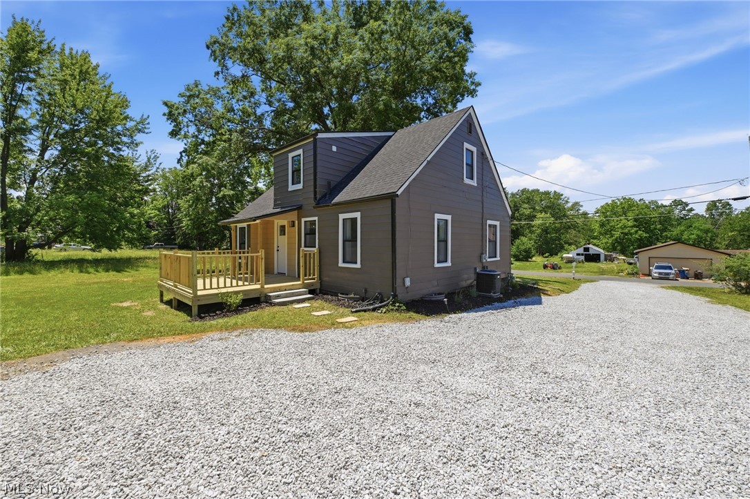 951 Bey Road Akron, OH 44312 - Photo 30 of 34 Side of structure featuring a dark gray exterior, white trim windows, a light wood-finish back deck with railing, and a dark shingle roof