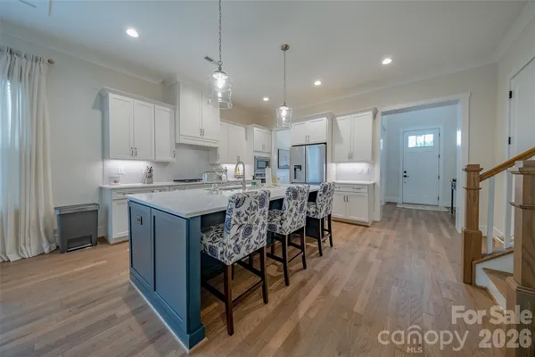 a kitchen with stainless steel appliances kitchen island granite countertop a table chairs refrigerator and microwave