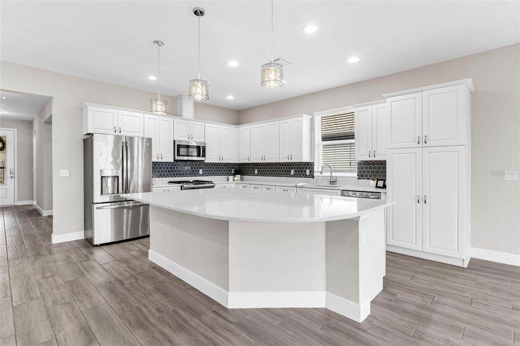 224 Silver Maple Road Groveland, FL 34736 - Photo 16 of 54 a kitchen with stainless steel appliances kitchen island granite countertop a refrigerator a stove a sink and white cabinets with wooden floor