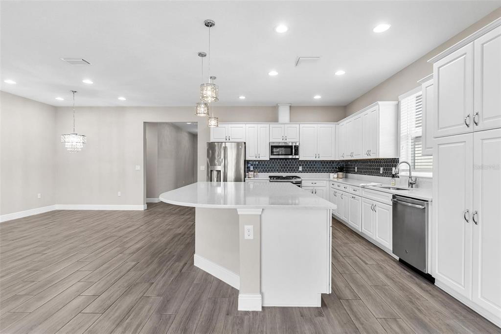 224 Silver Maple Road Groveland, FL 34736 - Photo 17 of 54 a kitchen with stainless steel appliances kitchen island granite countertop a stove a sink a refrigerator and white cabinets with wooden floor