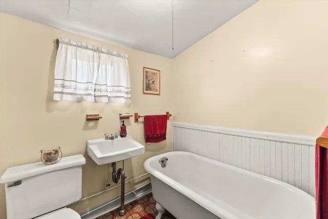 a bathroom with a bathtub a sink a toilet and a window