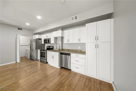 a kitchen with granite countertop white cabinets and stainless steel appliances