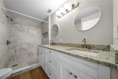 a bathroom with a granite countertop sink a mirror and a shower