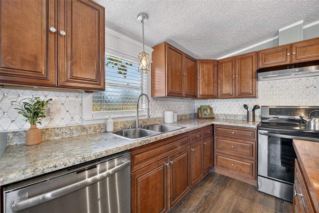 449 Big Salty Lane Springtown, TX 76082 - Photo 10 of 25 Kitchen featuring warm wood cabinetry, granite-finish countertops, stainless steel appliances, and a decorative tile backsplash