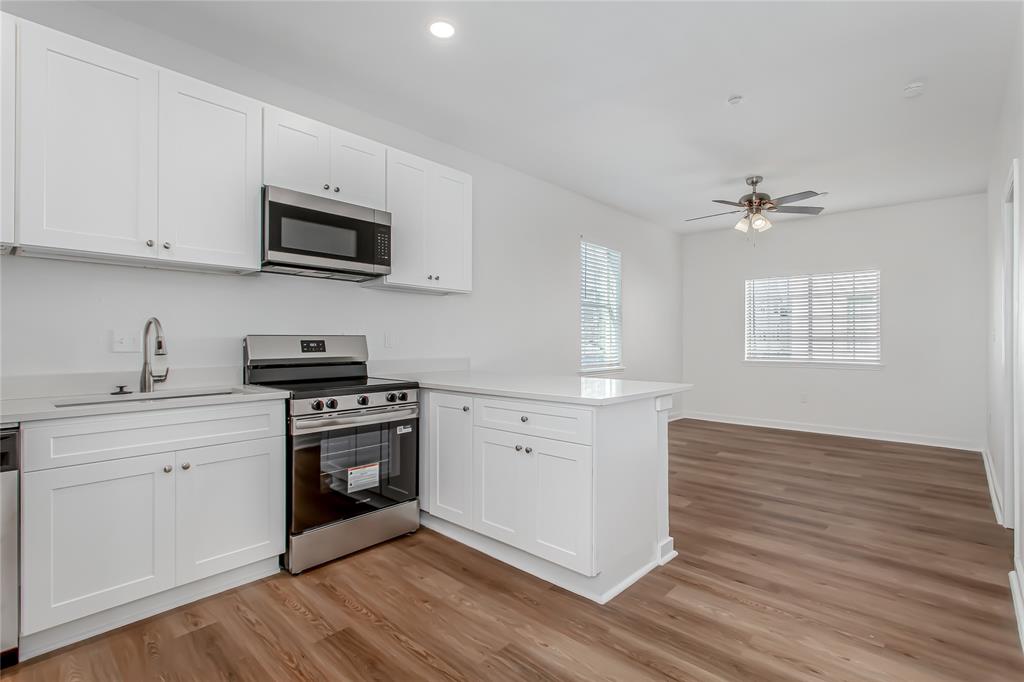 4713 Virginia Avenue, Unit E Dallas, TX 75204 - Photo 1 of 1 a kitchen with stainless steel appliances a white stove top oven cabinets and a wooden floor