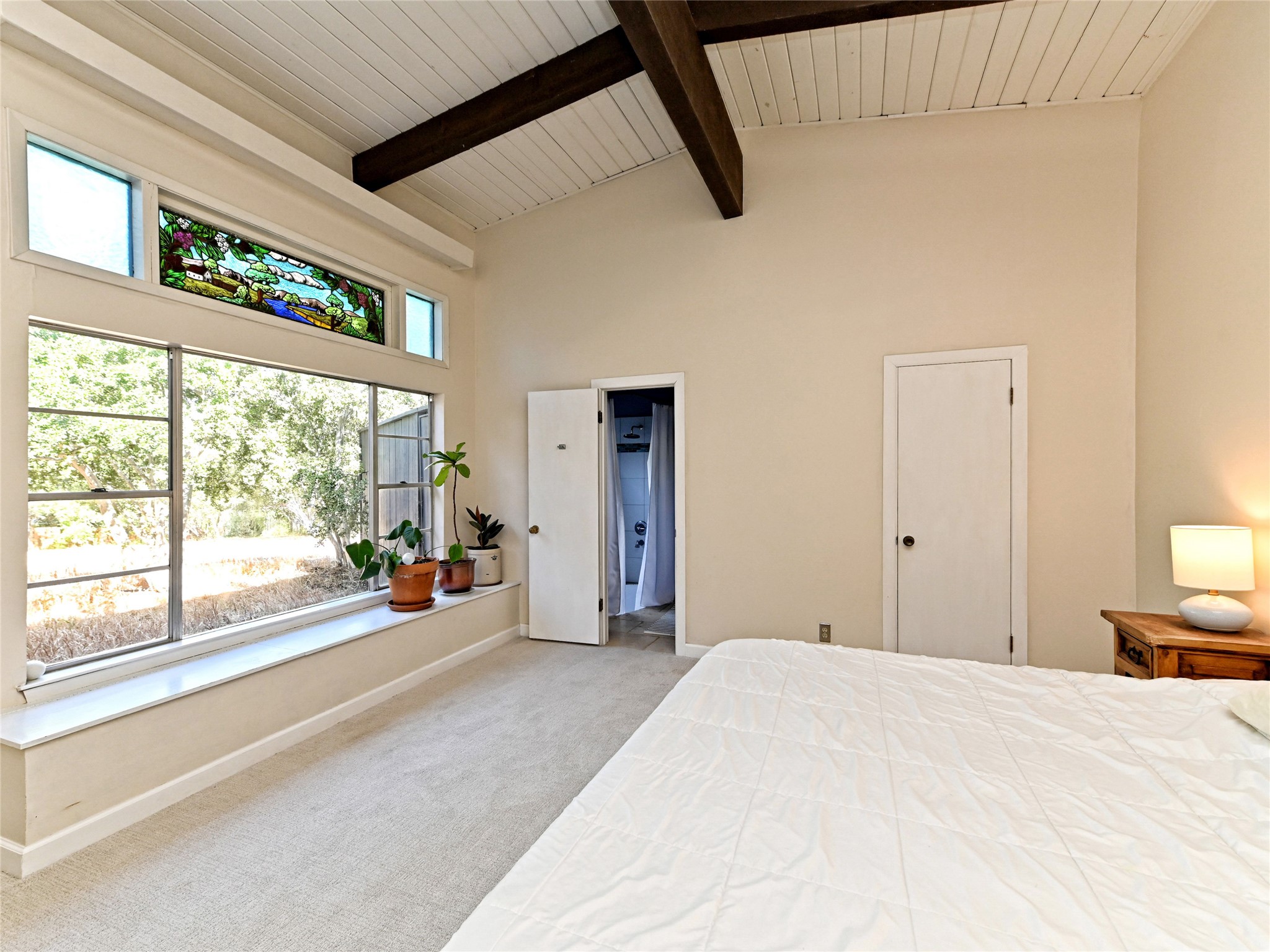 115 Snapper Street Lakeway, TX 78734 - Photo 18 of 30 A tranquil bedroom features a high vaulted ceiling, exposed wooden beams, and a stained glass transom window.