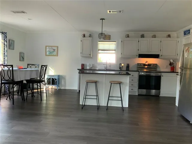 a kitchen with granite countertop a stove chairs and wooden floor