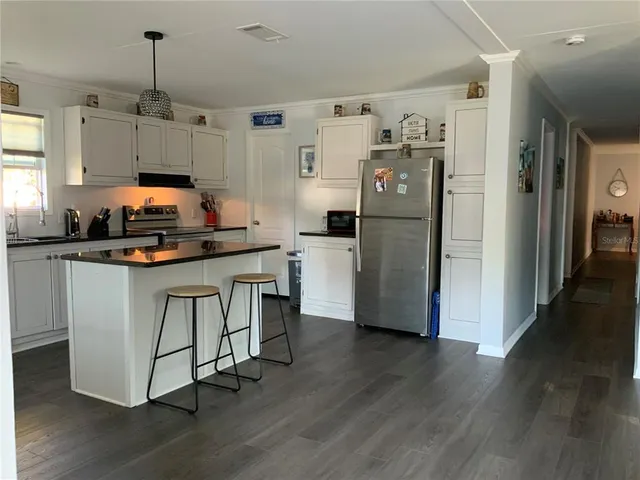 a kitchen with stainless steel appliances a refrigerator a stove a sink dishwasher and white cabinets with wooden floor