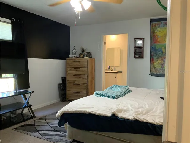a bedroom with a bed and a flat tv screen on dresser