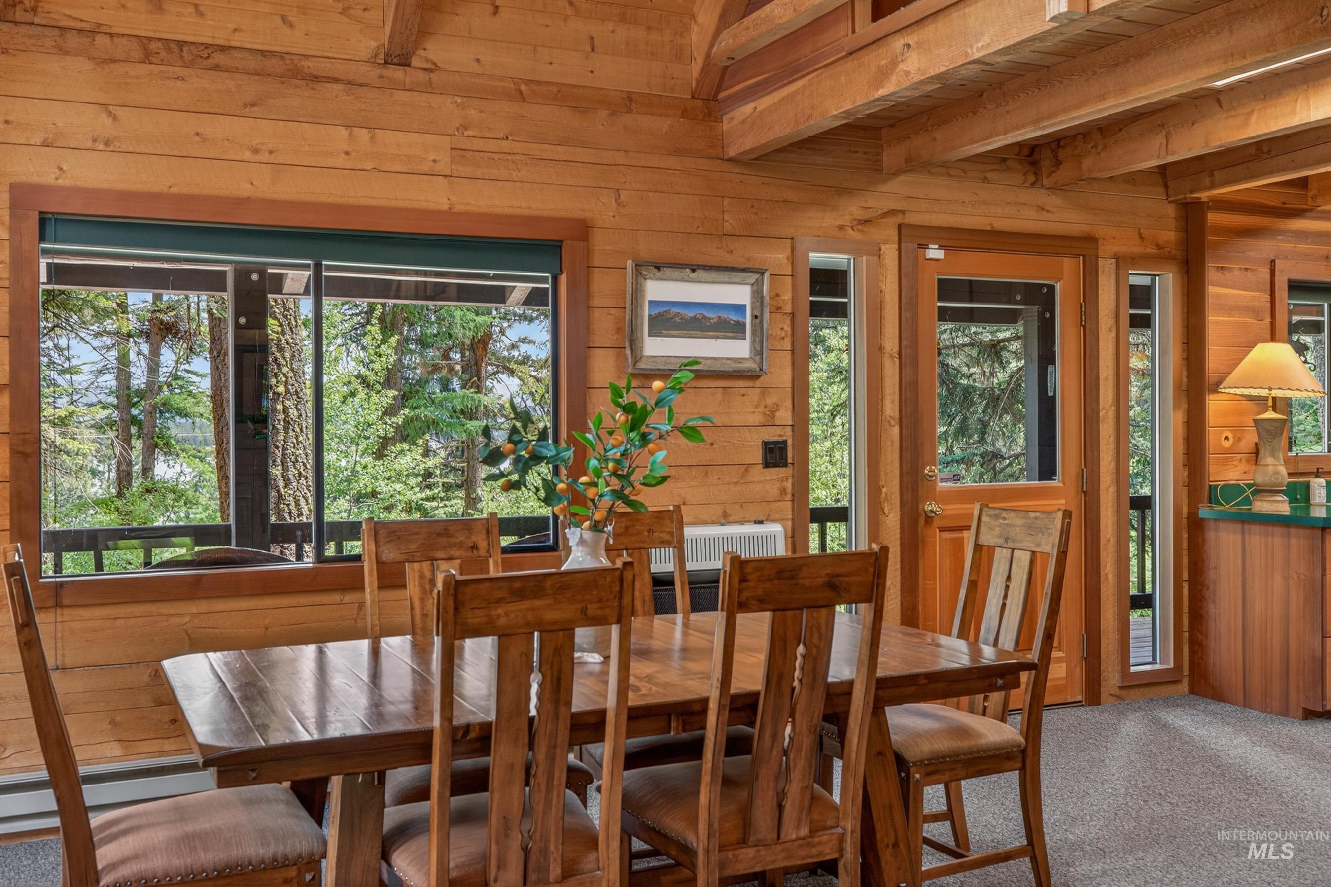 2339 West Mountain Road Donnelly, ID 83615 - Photo 4 of 37 Wood-paneled room featuring exposed wood beams and a large window overlooking a wooded landscape