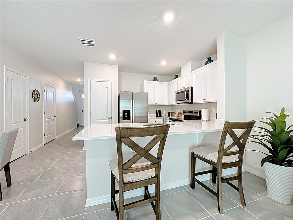 3140 Goose Road Davenport, FL 33837 - Photo 14 of 40 a kitchen with stainless steel appliances kitchen island granite countertop a refrigerator and chairs