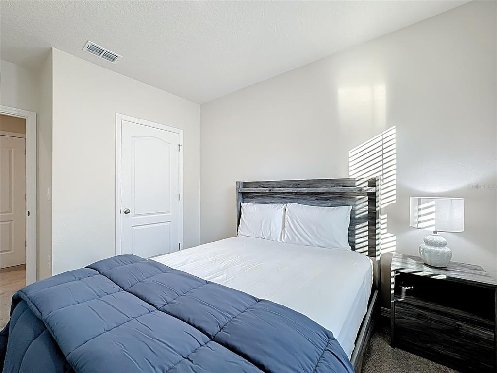 3140 Goose Road Davenport, FL 33837 - Photo 18 of 40 a bedroom with a bed and lamps