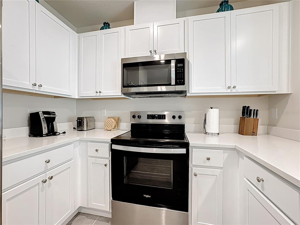 3140 Goose Road Davenport, FL 33837 - Photo 10 of 40 a kitchen with white cabinets and black appliances