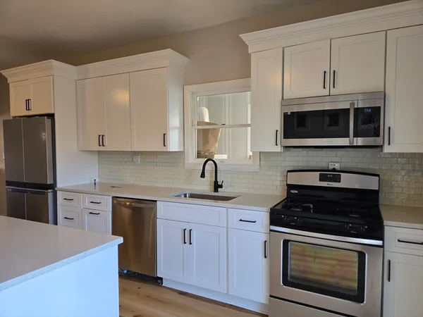 a kitchen with cabinets stainless steel appliances a sink and wooden floor