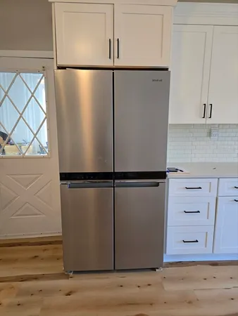 a view of a refrigerator in kitchen with stainless steel appliances wooden cabinet and view of cabinet