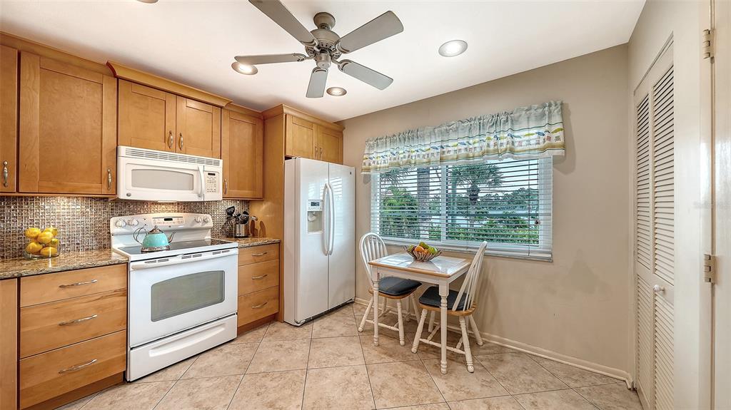 6204 Midnight Pass Road, Unit 205 Sarasota, FL 34242 - Photo 18 of 62 a kitchen with stainless steel appliances kitchen island granite countertop a refrigerator a stove a sink with a dining table and chair