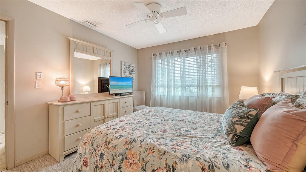 6204 Midnight Pass Road, Unit 205 Sarasota, FL 34242 - Photo 28 of 62 a spacious bedroom with a large bed and a chandelier