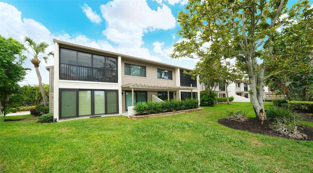 6204 Midnight Pass Road, Unit 205 Sarasota, FL 34242 - Photo 31 of 62 a view of a brick house with a big yard and large trees