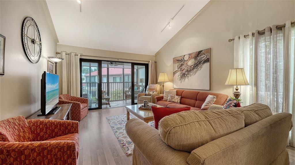 6204 Midnight Pass Road, Unit 205 Sarasota, FL 34242 - Photo 9 of 62 a living room with furniture a large window and a chandelier