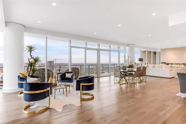a living room with furniture large window and view of kitchen