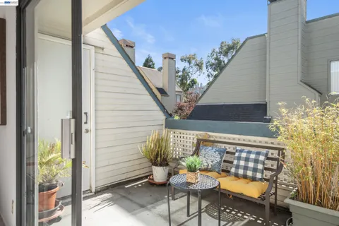 a balcony with chairs and potted plants
