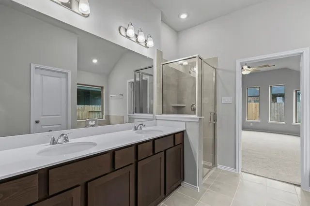 a bathroom with a double vanity sink a mirror and a shower