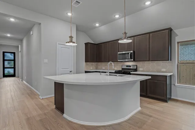 a kitchen with kitchen island a sink stainless steel appliances and cabinets
