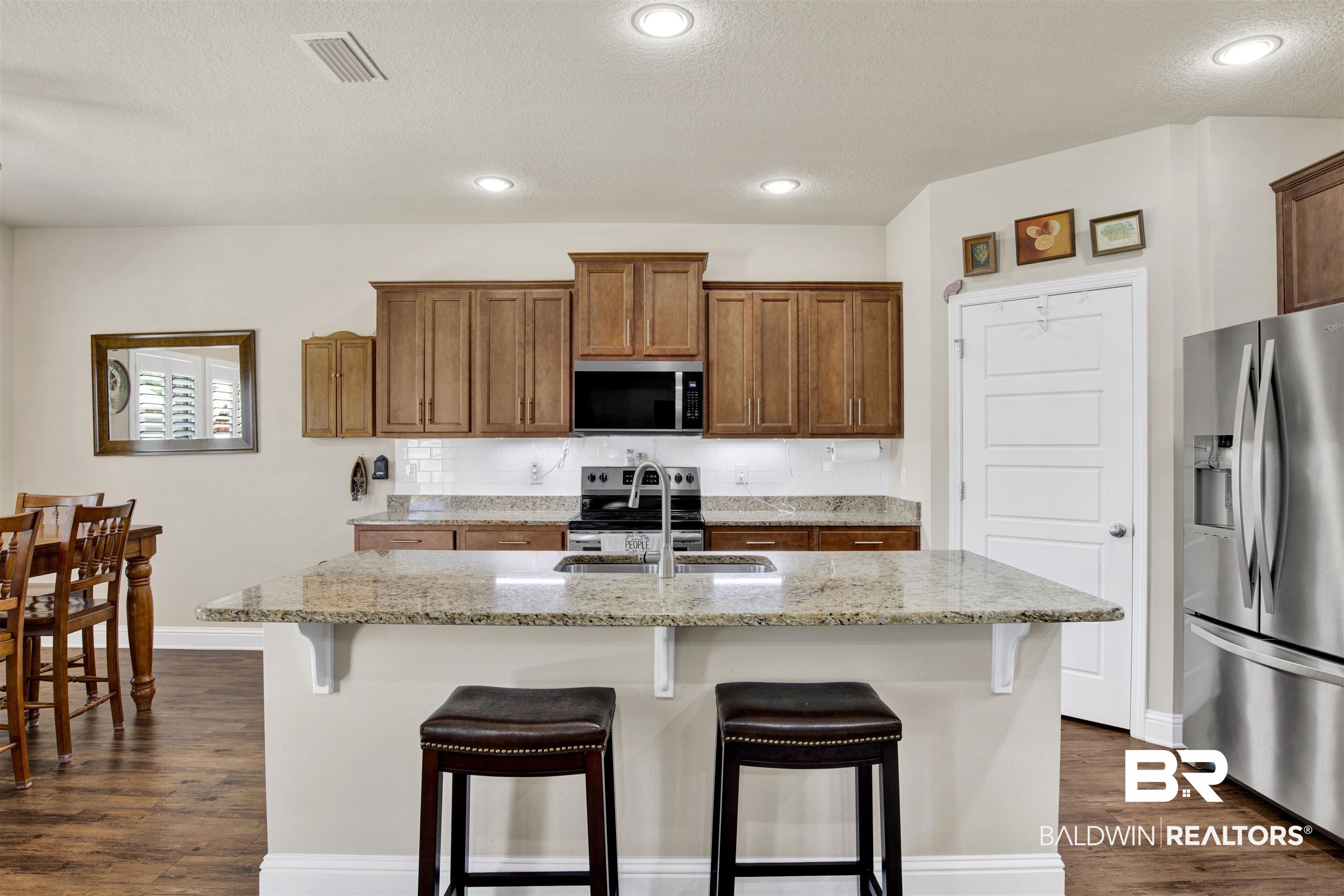 278 Silo Loop Fairhope, AL 36532 - Photo 6 of 26 Kitchen with stainless steel appliances, dark wood-type flooring, a breakfast bar area, brown cabinets, and light stone countertops