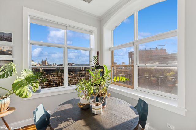 a dining room with furniture a potted plant and a floor to ceiling window