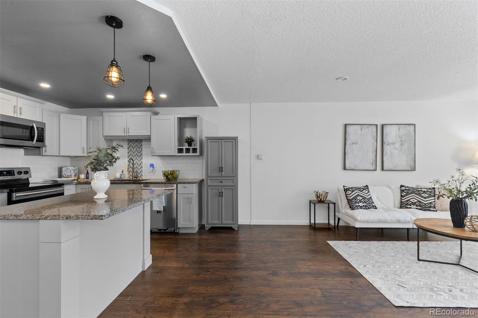 610 South Clinton Street, Unit 10A Denver, CO 80247 - Photo 4 of 40 a kitchen with kitchen island a white counter top space cabinets and stainless steel appliances