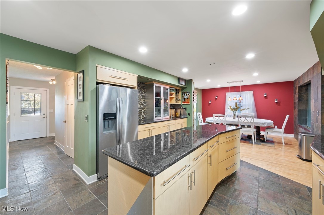 Kitchen featuring stainless steel fridge, a center island, granite counters, slate and hardwood floors