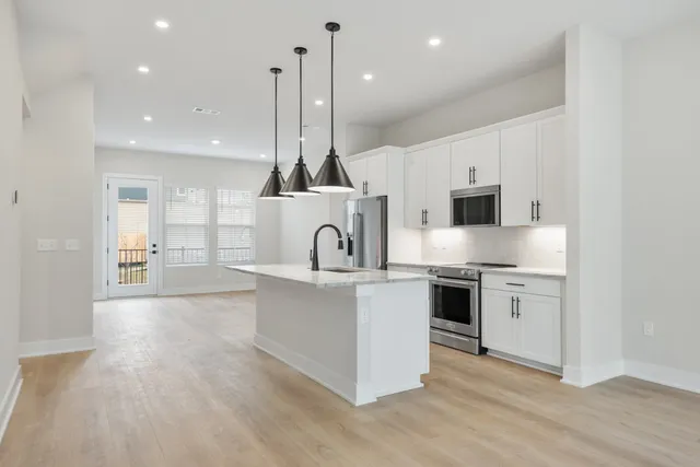 a large kitchen with stainless steel appliances granite countertop a stove and white cabinets